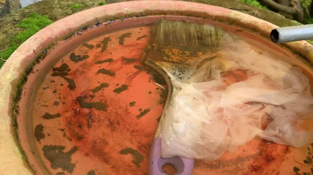 used paintbrush waste and puddle of rainwater, cause of mosquito larvae (aedes aegypti).
