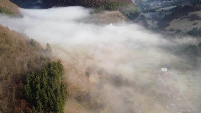 Aerial View of a Mountain Village in the Carpathians, Morning Fog Covers Houses, Fields, and Forests in the Valley