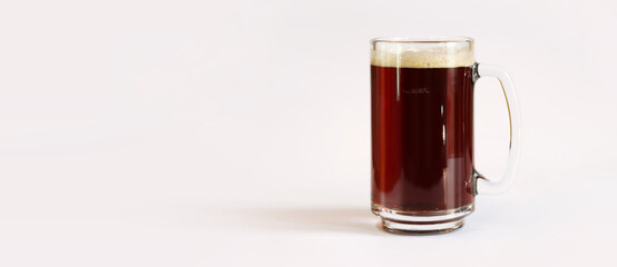 Kvass in a glass, light background. Glass of dark beer or kvass with foam in a glass on a light gray background. Traditional beer mug with a handle. Close-up on a glass with a cool tasty drink
