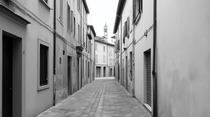 Narrow, quiet cobblestone street in historic European town, monochrome.