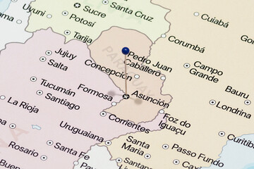 Macro photo of Asuncion city with a blue pin needle into Paraguay country political map