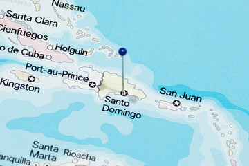 Macro photo of a blue pin needle into Santo Domingo city of Dominican Republic political map 