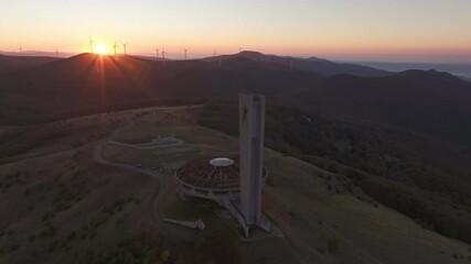 Kran, Bulgaria - 01 December 2024: Aerial view of the abandoned buzludzha monument at sunrise with wind turbines and mountains, Kran, Bulgaria.