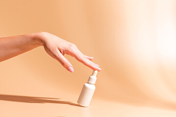 Woman hand touch white bottle of cosmetic serum
