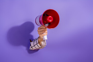 Hand holding a red megaphone against purple background, symbolizing announcement and communication
