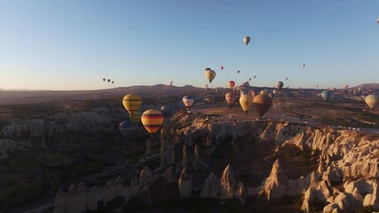 Goreme, Turkey - 01 December 2024: Aerial view of love valley with colorful hot air balloons and fairy chimneys at sunrise, Goreme, Turkey.