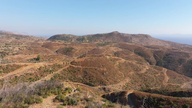 Aerial view of rugged mountainous terrain with a winding road in a serene countryside landscape, Milas, Turkey.