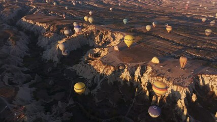 Goreme, Turkey - 01 December 2024: Aerial view of colorful hot air balloons over scenic love valley at sunrise with unique rock formations, Goreme, Turkey.