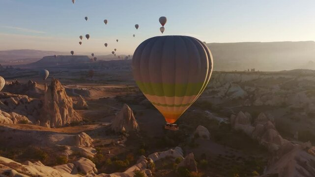 Goreme, Turkey - 01 December 2024: Aerial view of hot air balloons over love valley at sunrise with stunning rock formations, Goreme, Turkey.