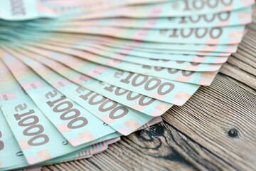 Big amount of ukrainian new one hundred hryvnia money bills with modern design on wooden background. Financial concept, business