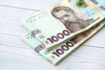 Big amount of ukrainian new one hundred hryvnia money bills with modern design on white wooden table. Financial concept, business