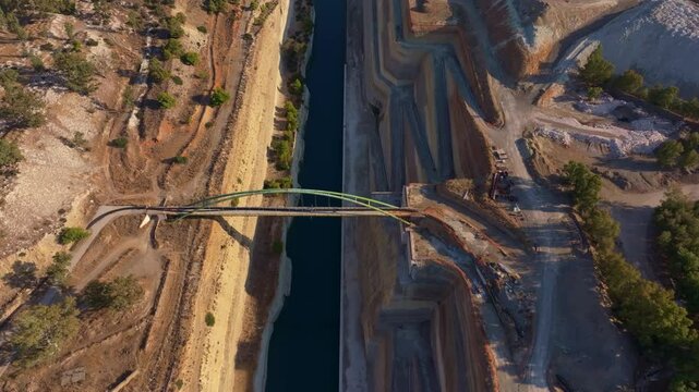 Aerial view of Corinth Canal with a beautiful bridge and water surrounded by natural landscape, Corinth, Greece.