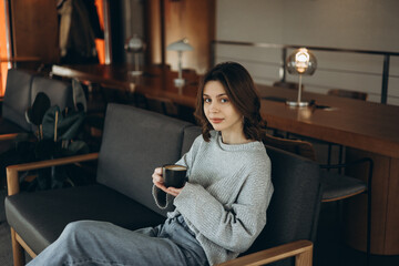 A girl in a cafe drinks coffee and enjoys a rest. Morning in a coffee shop.
