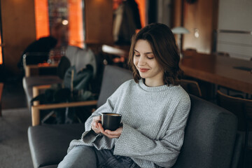 A girl in a cafe drinks coffee and enjoys a rest. Morning in a coffee shop.