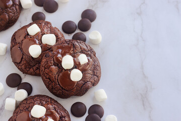 Homemade chocolate brownie cookies decorating with marshmallow on top on white marble table.