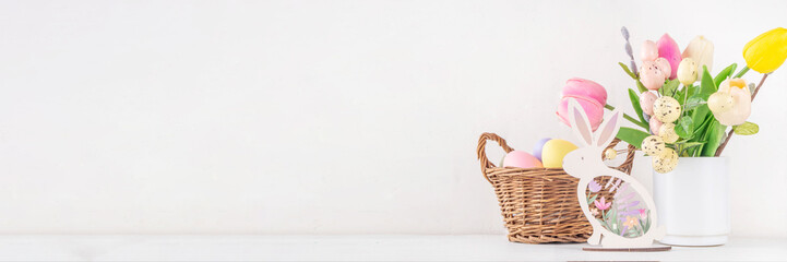 Spring Easter holiday table still life with painted Easter eggs, spring flowers bouquet, decorative bunny rabbits, on white kitchen background 