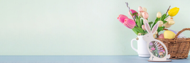Spring Easter holiday table still life with painted Easter eggs, spring flowers bouquet, decorative bunny rabbits, on white kitchen background 