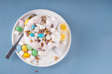 Easter hot chocolate with whipped cream, marshmallow and crushed chocolate mini eggs, on colorful table background, with ingredients, copy space