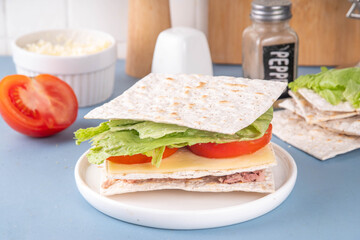 Tasty matzah sandwich with tuna, cheese, lettuce and vegetables. Viral club sandwich for Passover. Food ideas and recipe for Jewish Pesach holiday
