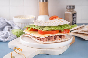 Tasty matzah sandwich with tuna, cheese, lettuce and vegetables. Viral club sandwich for Passover. Food ideas and recipe for Jewish Pesach holiday