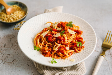 Vegane rote Linsen Bolognese mit Spagetti auf einem weißen Teller. Gesunde Ernährung, Fleischlos.