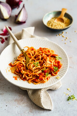 Rote Linsen Bolognese mit Spagetti auf einem weißen Teller. Veganes Essen.