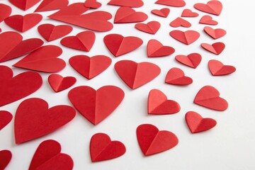 A scattering of crimson hearts, a romantic arrangement of paper hearts on a white background