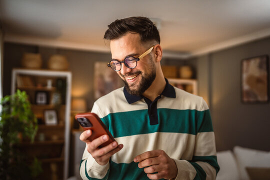 portrait of adult man stand and use mobile phone at home
