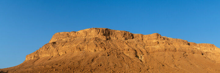 Panorama of the Judean Desert mountains behind the Ein Bokek hotel area at the Dead Sea in Israel at sunrise.
