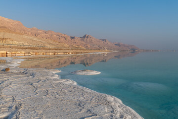 Salt formations on the shore of the Dead Sea and the Judean Desert mountains in Israel.
