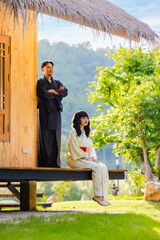A vertical shot of Enjoying nice time on fresh air. Asian couple wearing klimono express felling happy smile at Traditional Japanese house with garden.