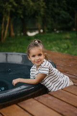 .portrait of a happy 5-6 year old girl posing for a photo in the backyard of a country house