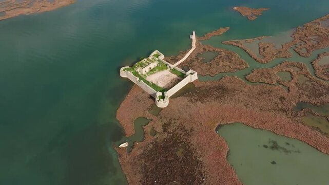 Aerial view of Ali Pasha's Castle on the serene Lake Butrint with clear water and lush wetlands, Ksamil, Albania.