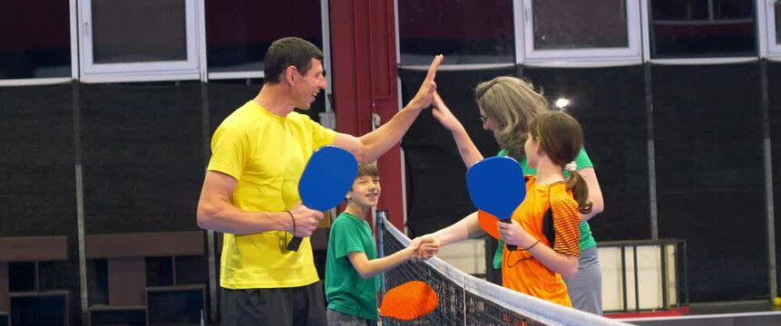 A man and a child playing pickleball on a blue, inside court