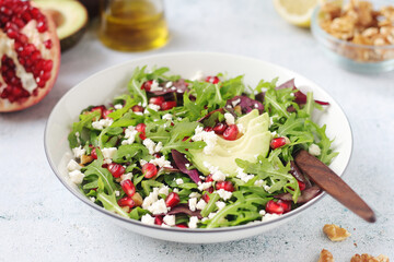 A plate with green rocket salad with pomegranate and avocado	