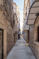 Obraz premium Morning walk along a romantic narrow street in the old town of Trogir on the Adriatic coast, Dalmatia, Croatia