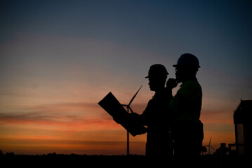 Silhouettes of engineers and technicians are working hard to ensure the successful creation of renewable energy from wind turbines.