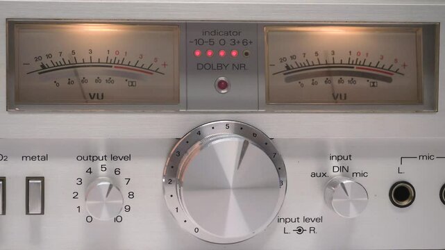 Close-up of a vintage audio mixer with illuminated vu meters indicating a constant signal and various knobs and inputs