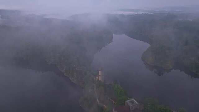 Aerial view of Zvikov Castle surrounded by the serene Moldau river and misty forest at sunrise, Zvikovske Podhradi, Czech Republic.