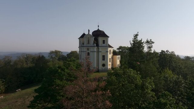 Aerial view of the historic Kostel sv. Jana Krtitele a Panny Marie Karmelske church surrounded by serene greenery and picturesque landscape, Smolotely, Czech Republic.