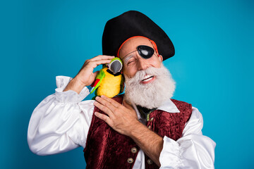 Photo portrait of bearded pirate man pet cute parrot toy wear hallooween costume isolated on blue color background