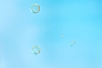 Minimalistic macro shot of clear oil or air bubbles suspended against a smooth blue gradient background, emphasizing simplicity and elegance