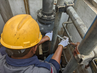 Construction Worker in a Hard Hat Fixing Pipes