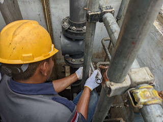 Worker inspecting a valve on a pipe