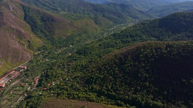 Aerial view of a picturesque village nestled in a lush valley with a serene vit river and surrounded by majestic mountains, Glozhene, Bulgaria.