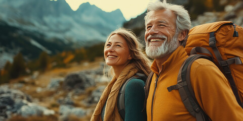 Senior couple happily hiking in the mountains, enjoying nature and each other's company. Their smiles show love and joy in retirement, surrounded by autumn scenery
