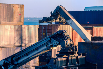 Reach stacker arm handling shipping containers at a port facility