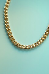Obraz premium A golden chain necklace artfully displays its links against a soft, light blue backdrop