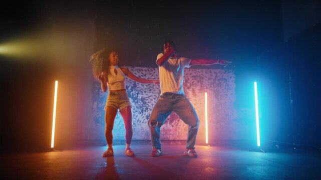 Hip-hop dancers moving rhythmically on dancefloor, joyful black woman and man. Active dance of professional dancers, couple of African American lady and guy moving in dance studio, hobby and passion