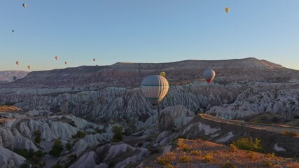 Goreme, Turkey - 01 December 2024: Aerial view of hot air balloons over a beautiful valley with majestic rock formations at sunrise, Goreme, Turkey.